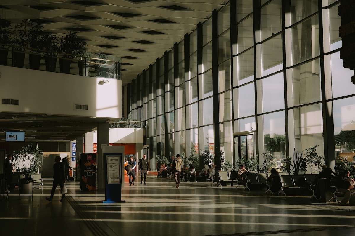 Saguão contemporâneo de aeroporto com luz natural e pessoas em trânsito